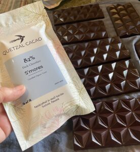 Quetzal Cacao 82% dark chocolate S’mores bar beside finished small-batch chocolate bars, handcrafted from certified organic cacao in Sortová, Panama.